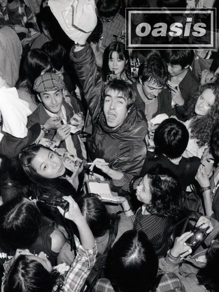 a group of people standing around each other in front of a sign that says oasis