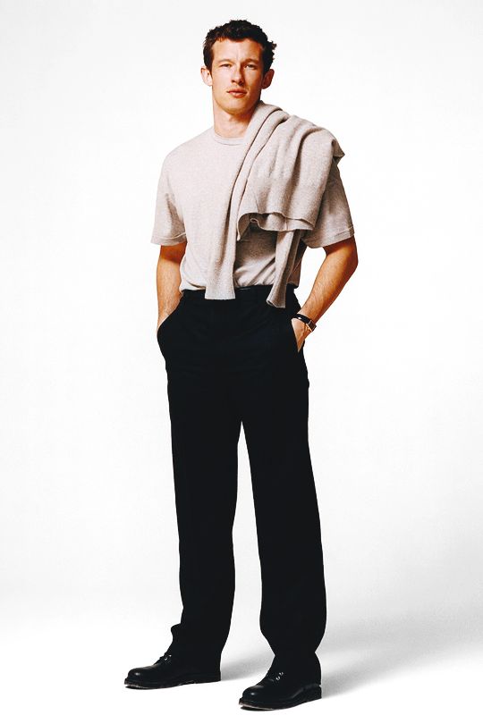 a man standing in front of a white background with his hands on his hips wearing black pants