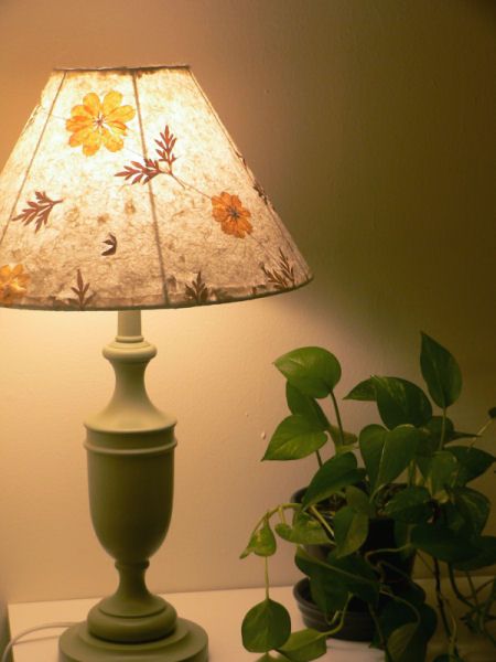 a green lamp sitting on top of a white table next to a potted plant