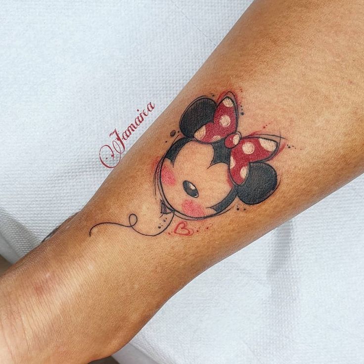 a person with a tattoo on their arm that has a minnie mouse design on it