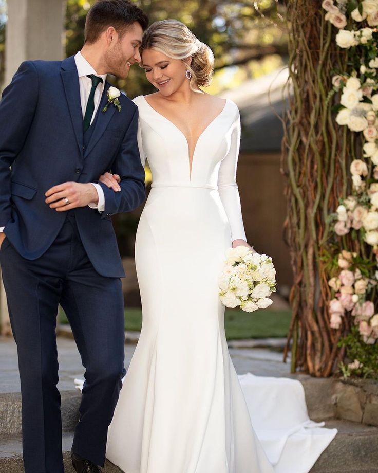 a bride and groom are walking down the steps together in front of an arch decorated with flowers