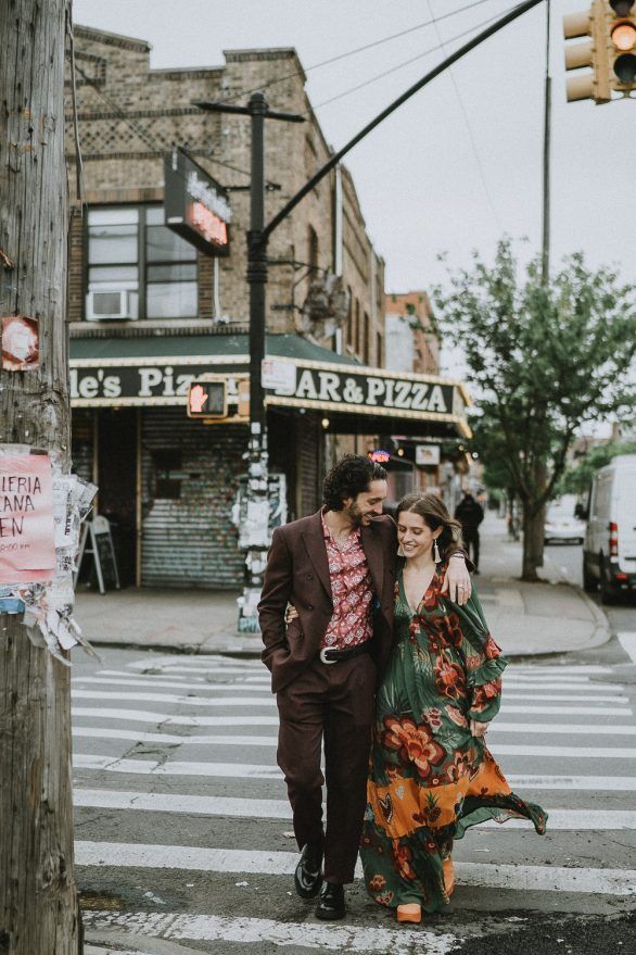 a man and woman walking across a street next to a traffic light on a cross walk