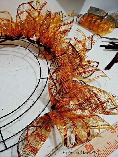 an orange wreath is sitting on a table next to scissors and other crafting supplies