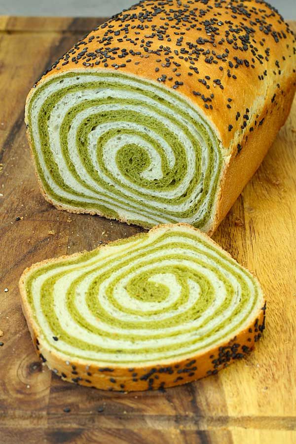 a sliced loaf of matcha swirl bread on top of a wooden cutting board with the words matcha swirl bread