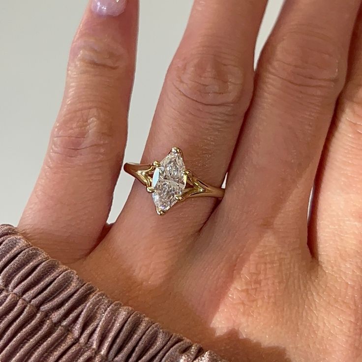 a woman's hand with a yellow gold ring on it and a diamond in the middle