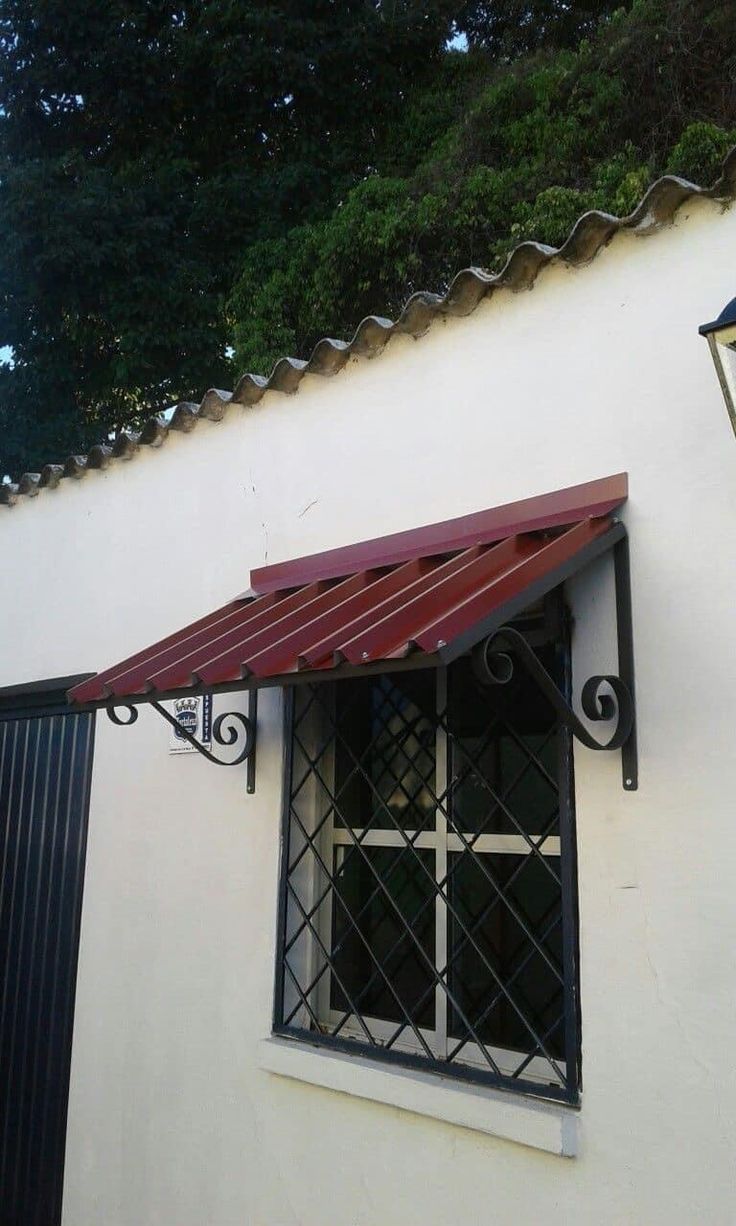 an open window on the side of a building with a red awning over it