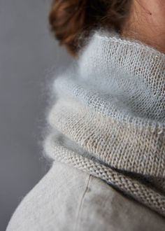 a close up of a woman wearing a white sweater with a knitted neck tie