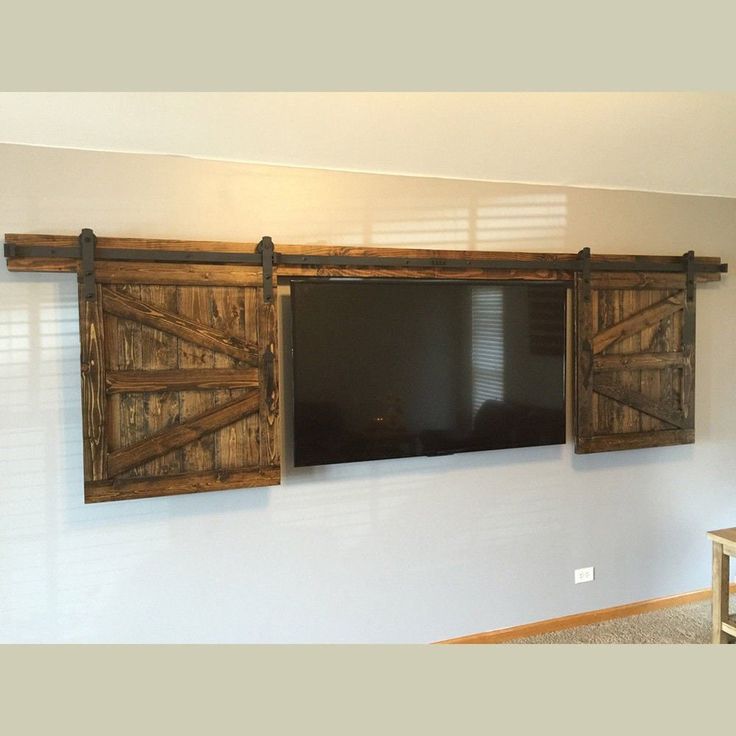 a flat screen tv mounted to the side of a wall next to wooden shutters