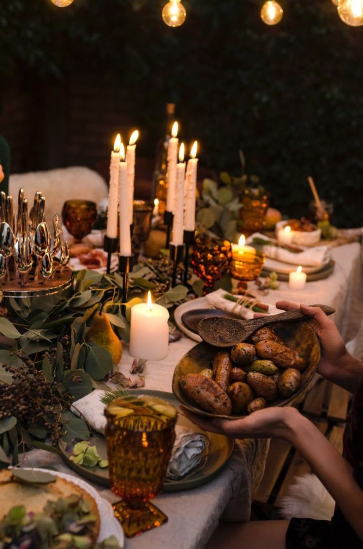 people sitting at a table with candles and food