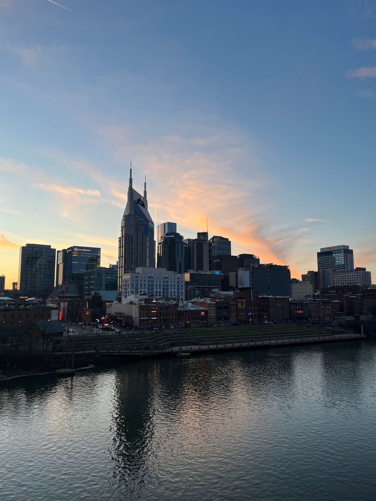 the city skyline is reflected in the water as the sun sets over the buildings on the other side