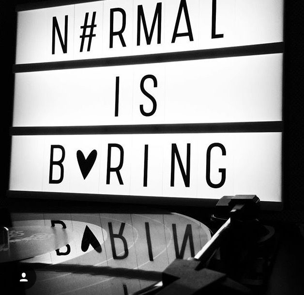 a black and white photo of a neon sign that reads normal is boring babyin