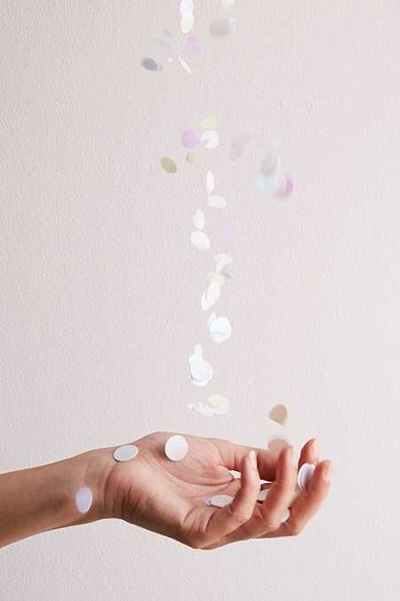 a woman's hand is throwing confetti into the air with her fingers