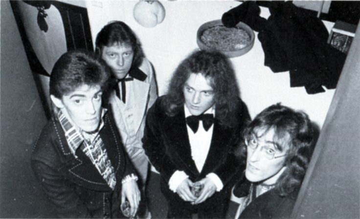 an old black and white photo of four men in tuxedos