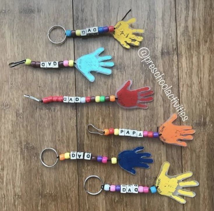 five different colored hand shaped key chains on a wooden table with the word love spelled in small letters