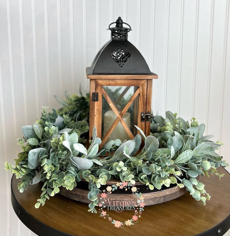 a wooden table topped with a lantern and greenery