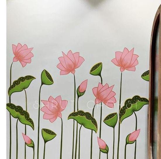 a wall with pink flowers painted on it and green leaves in the foreground, next to a mirror