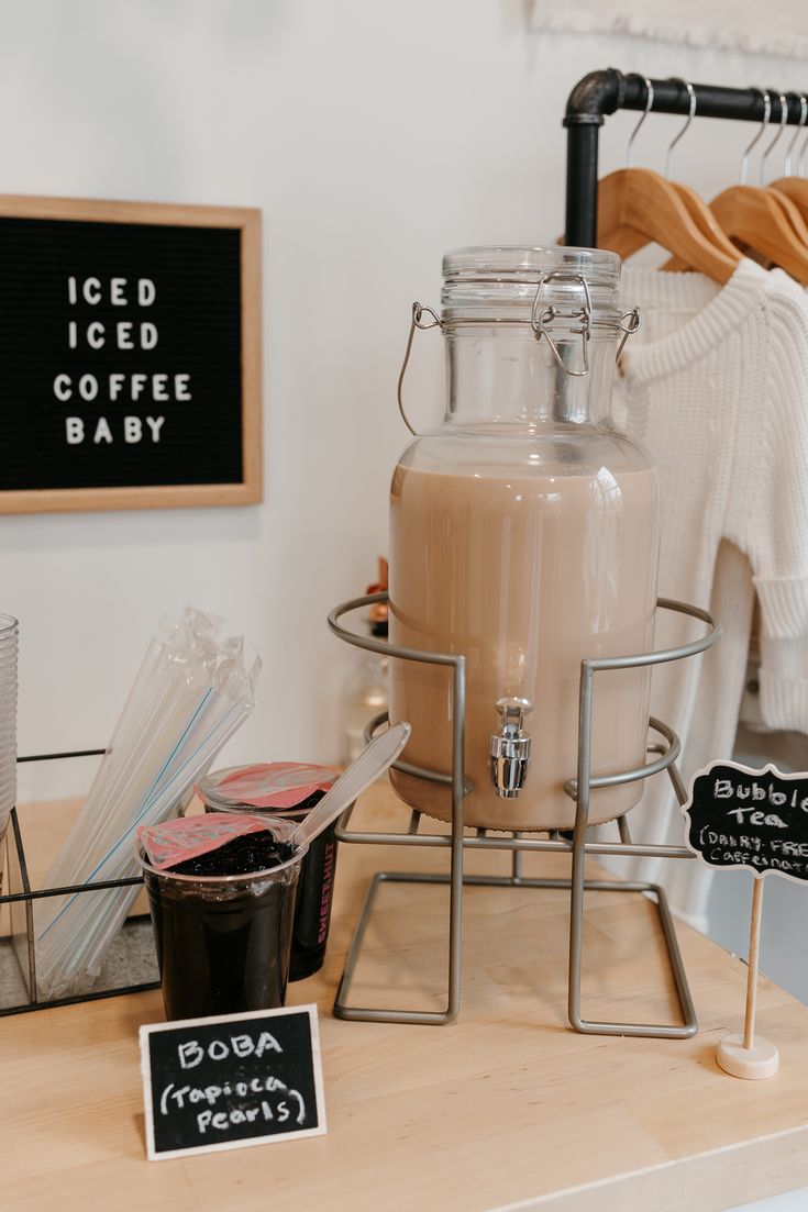 a coffee maker sitting on top of a wooden table next to a sign that says iced iced coffee baby