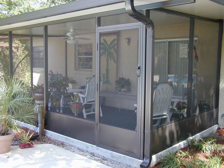 an enclosed patio area with chairs and potted plants on the side of the house