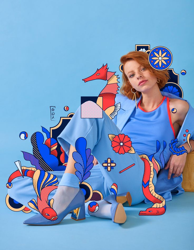 a woman is sitting on the floor with her legs crossed and wearing blue clothing, she has red hair