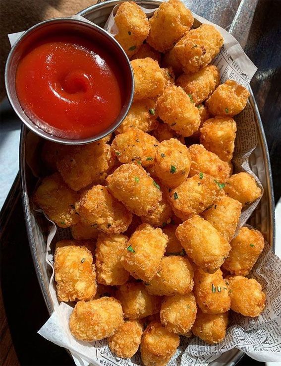 a basket filled with tater tots next to ketchup and dipping sauce