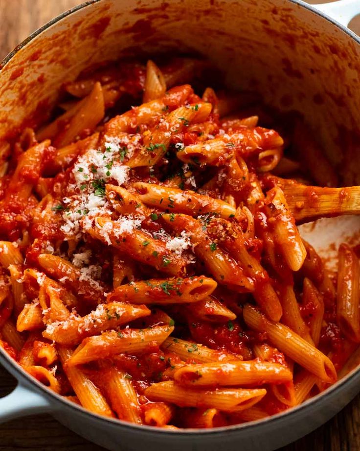 pasta with sauce and parmesan cheese in a pot on a wooden table top