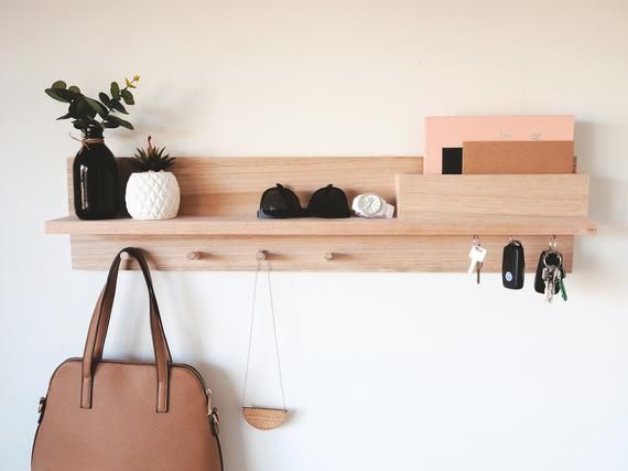 a purse hanging on the wall next to a wooden shelf with various items in it