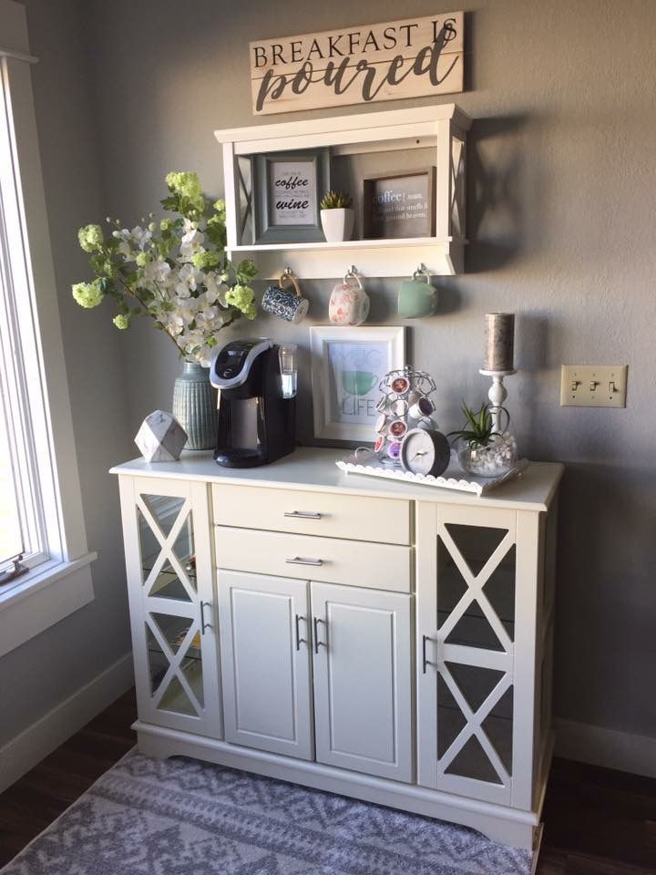 a white cabinet with flowers and pictures on it next to a window in a room