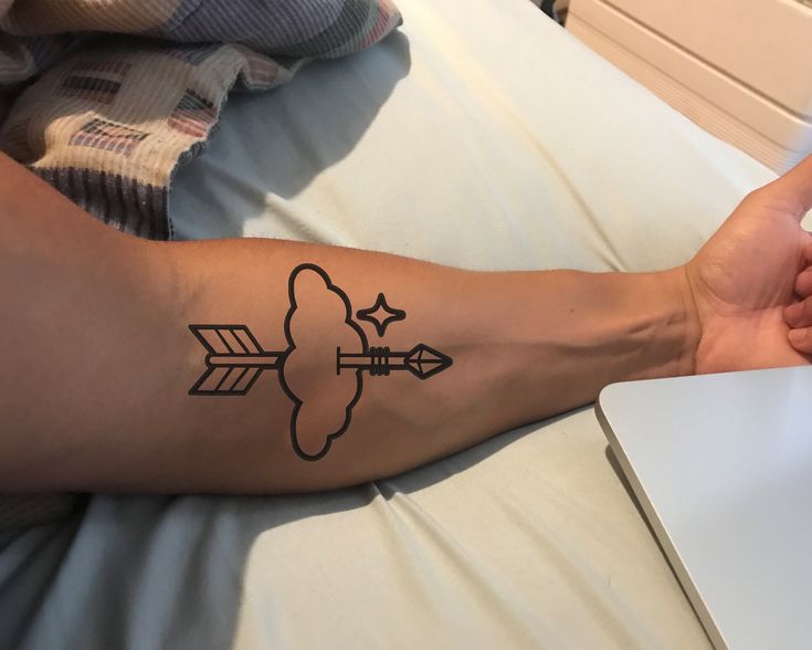 a person's arm with an arrow tattoo on the left side of their leg