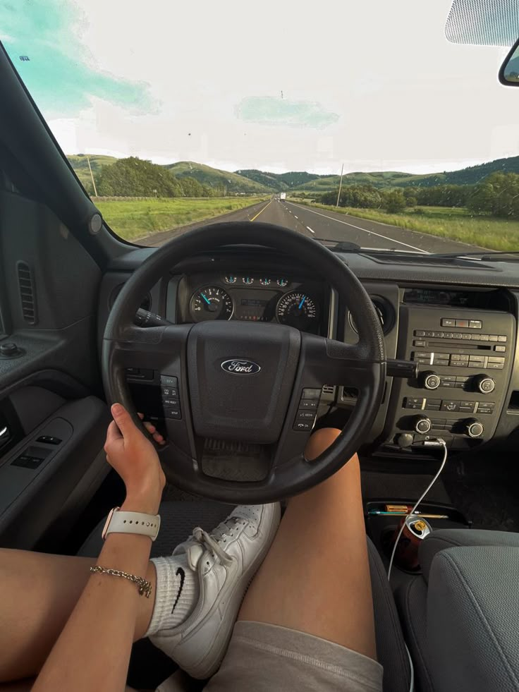 a woman is sitting in the driver's seat of a truck with her feet on the steering wheel