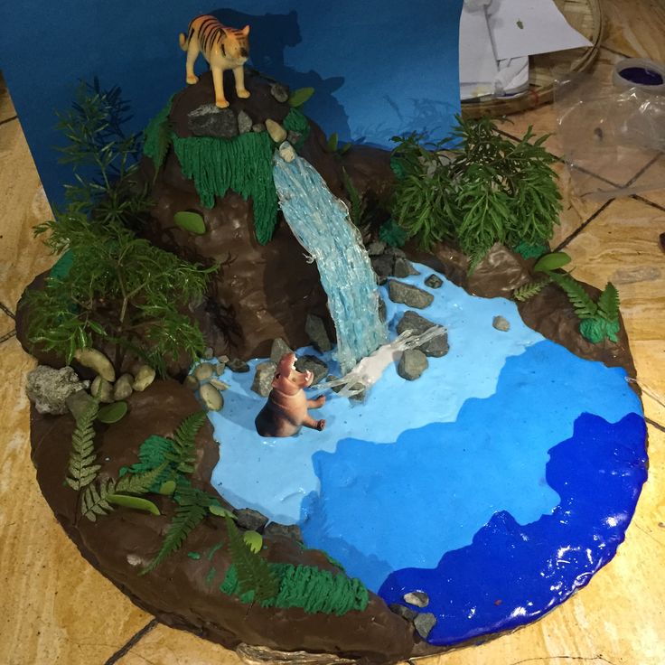 a cake that is shaped like a pond with animals on it and water running down the side