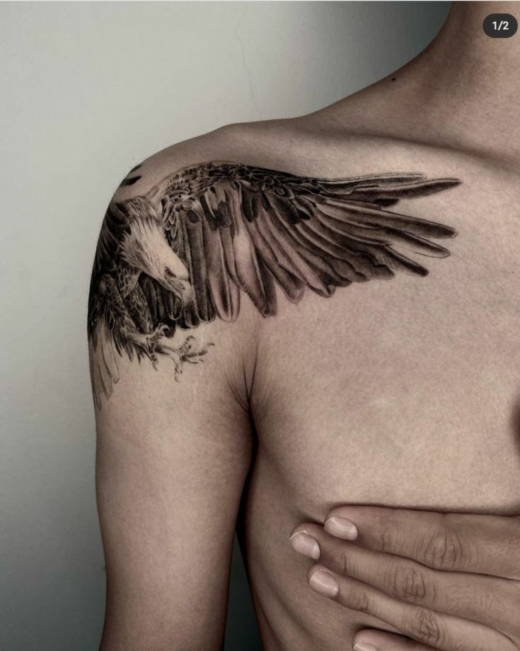 a man with an eagle tattoo on his chest is holding his hand to his chest