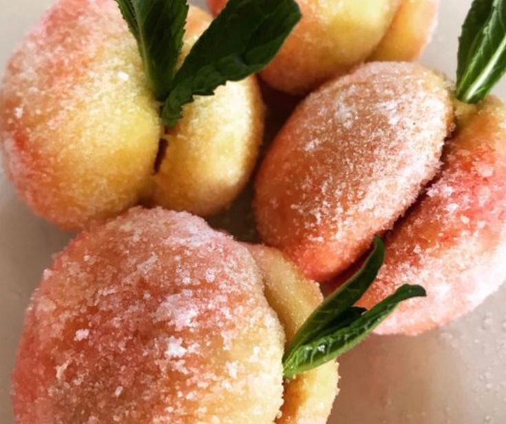 powdered sugar covered donuts with sprigs and leaves on the top one