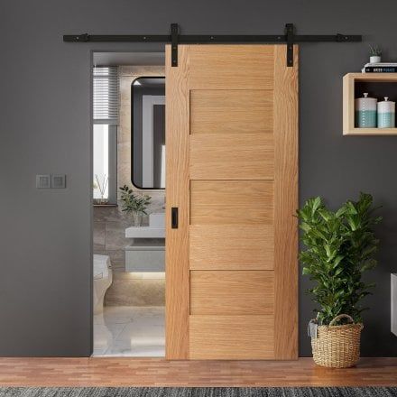 an open wooden door in a living room next to a potted plant and mirror