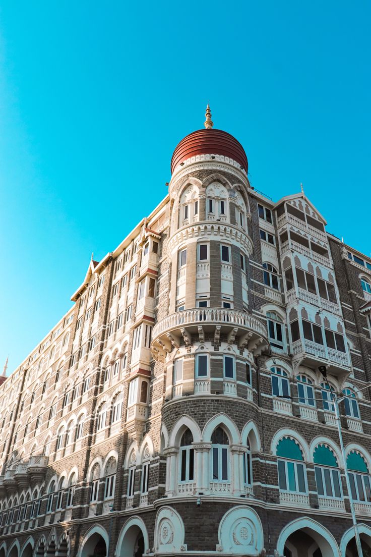 a large building with many windows and balconies on the top floor, in front of a blue sky