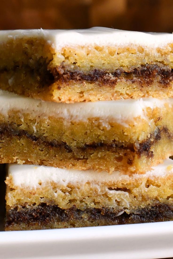 three pieces of cake stacked on top of each other in a white plate with icing