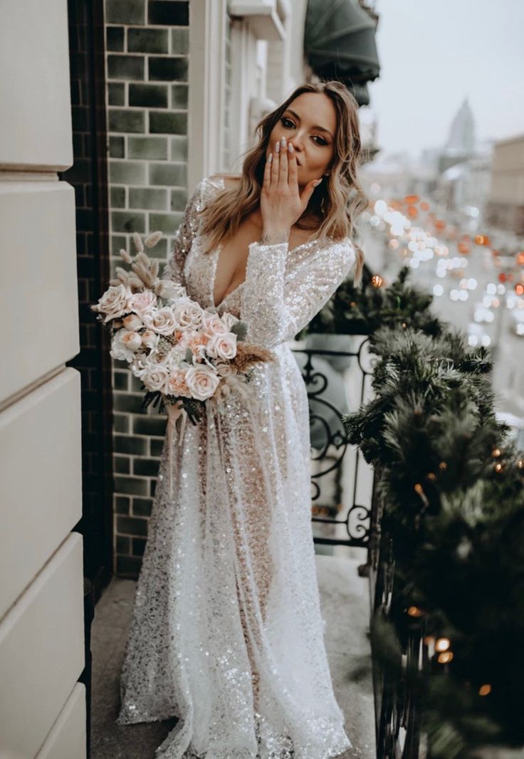 a woman in a white dress is standing on the sidewalk and talking on her cell phone