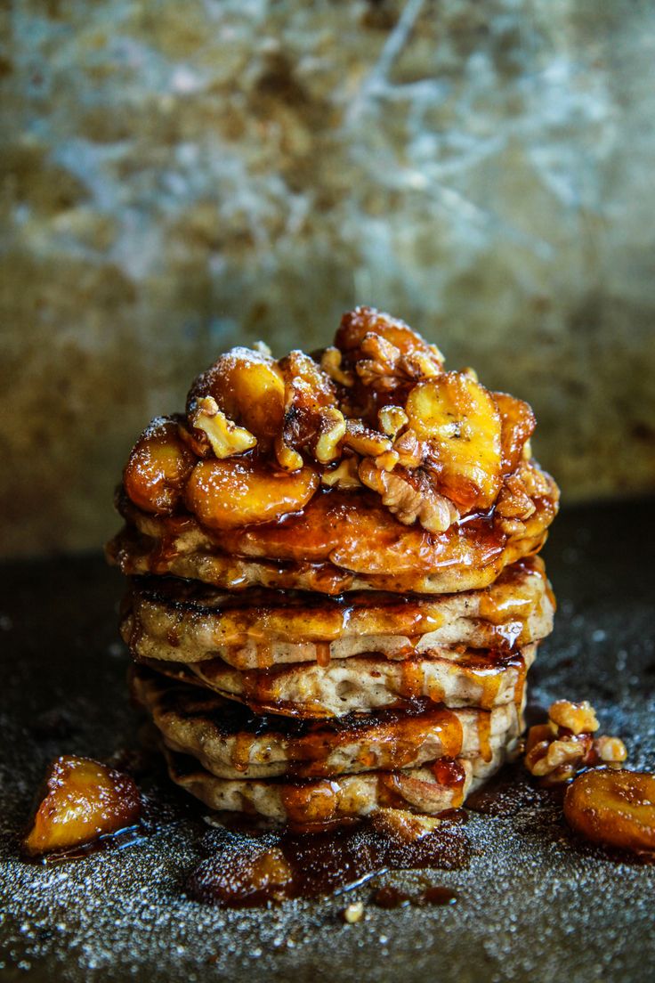 a stack of pancakes sitting on top of a table covered in syrup and walnuts