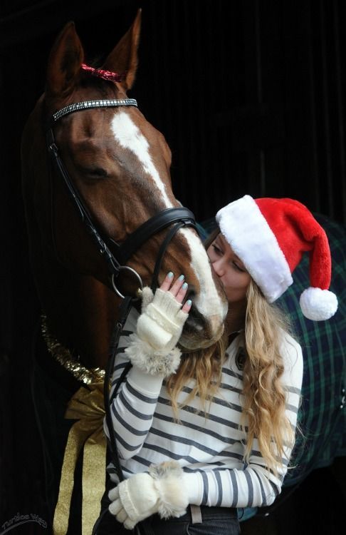 a woman in a santa hat kissing a horse