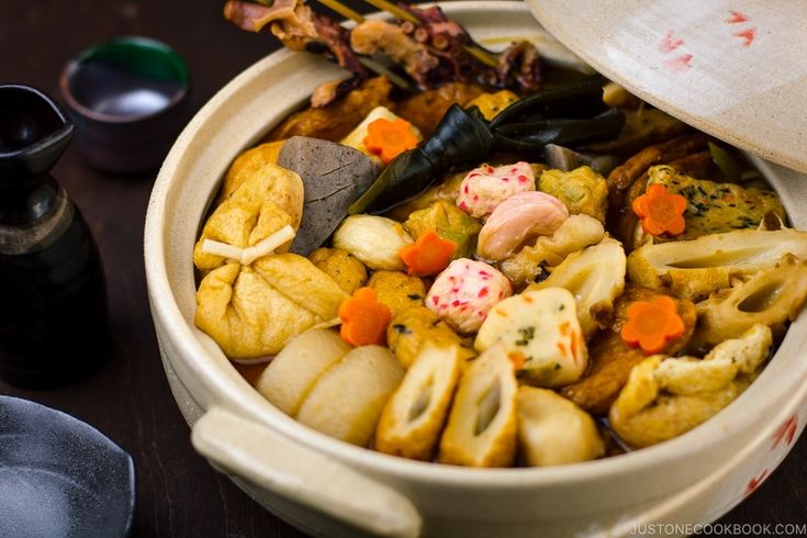 a white bowl filled with food on top of a wooden table next to other items