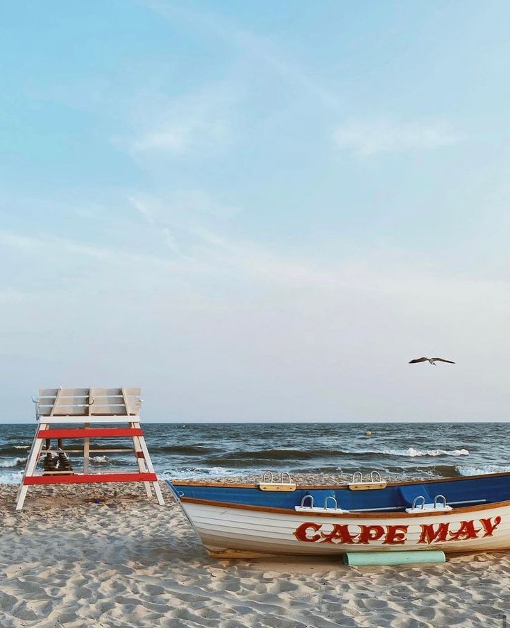 a boat sitting on top of a sandy beach next to the ocean