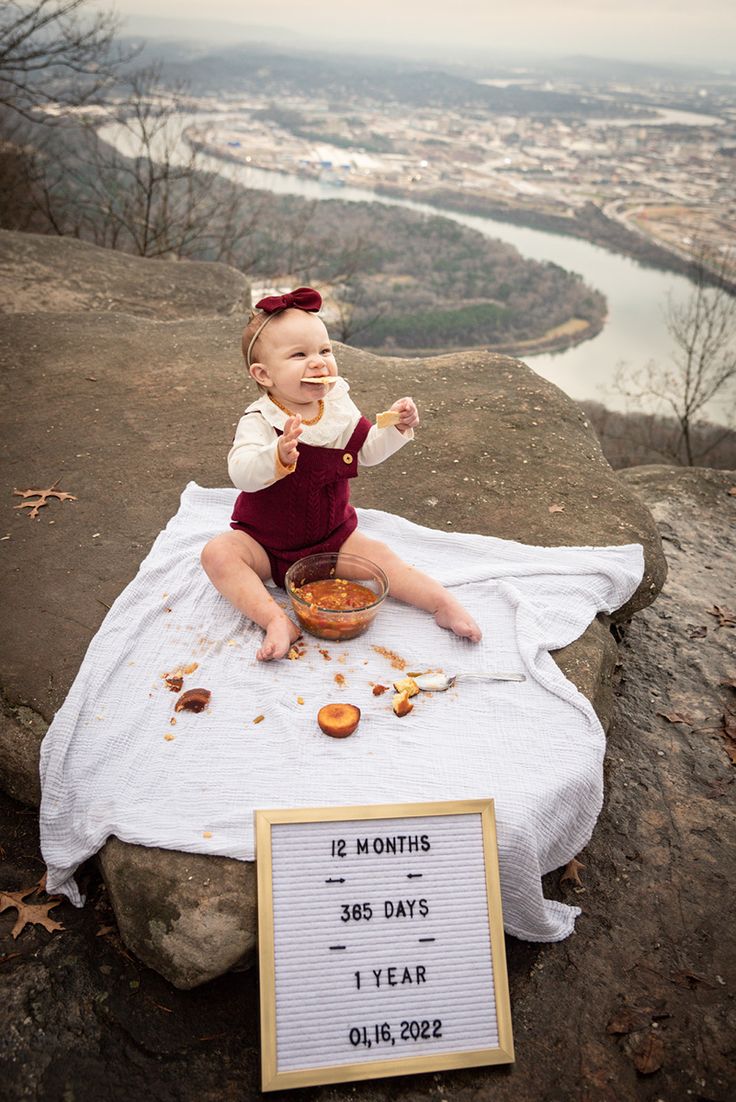 a baby sitting on top of a rock eating food