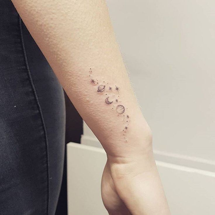 a woman's arm with the moon and stars tattoo on her left side forearm