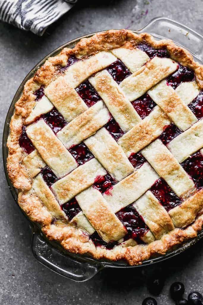 a pie with latticed crust and blueberries in the middle on a gray surface