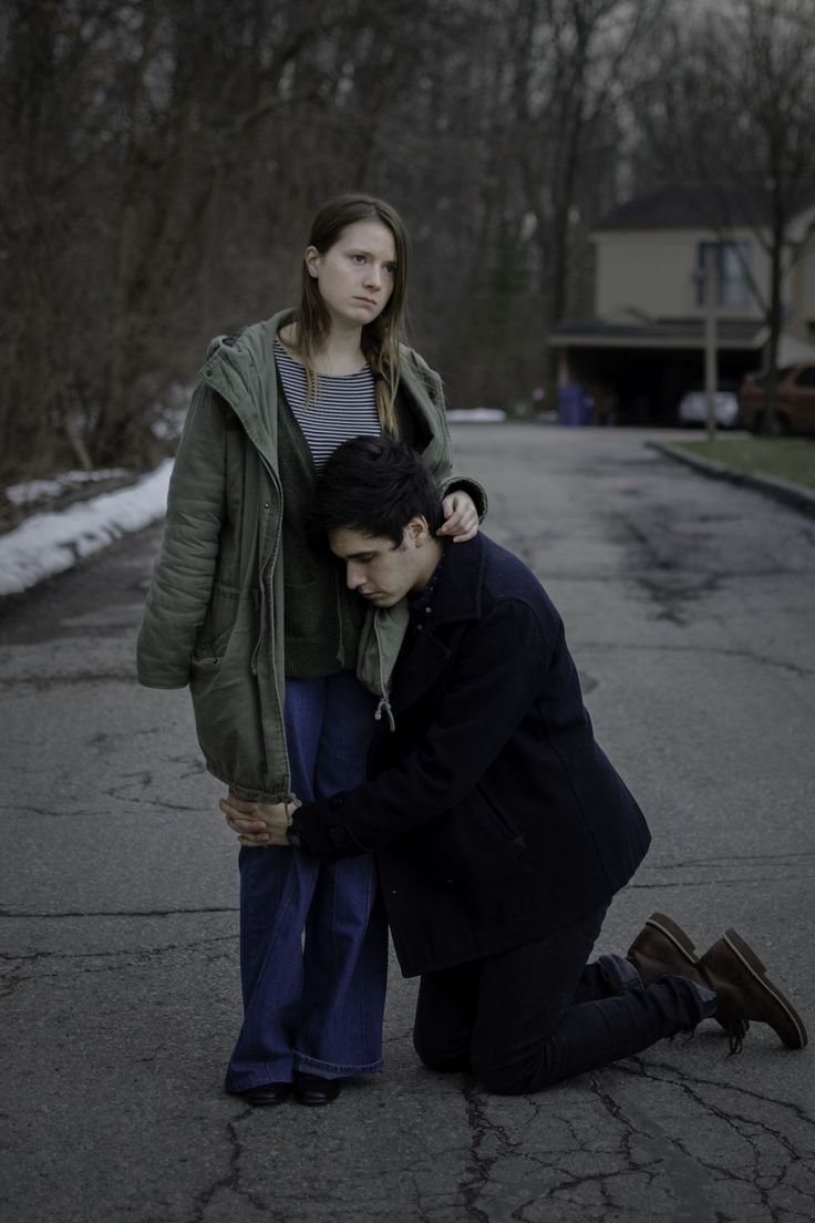 a man kneeling down next to a woman who is holding her hand on the ground