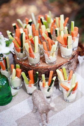 carrots and celery sticks are arranged in small cups on a picnic table