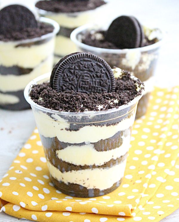 an oreo cookie dessert in a plastic cup on a yellow and white tablecloth