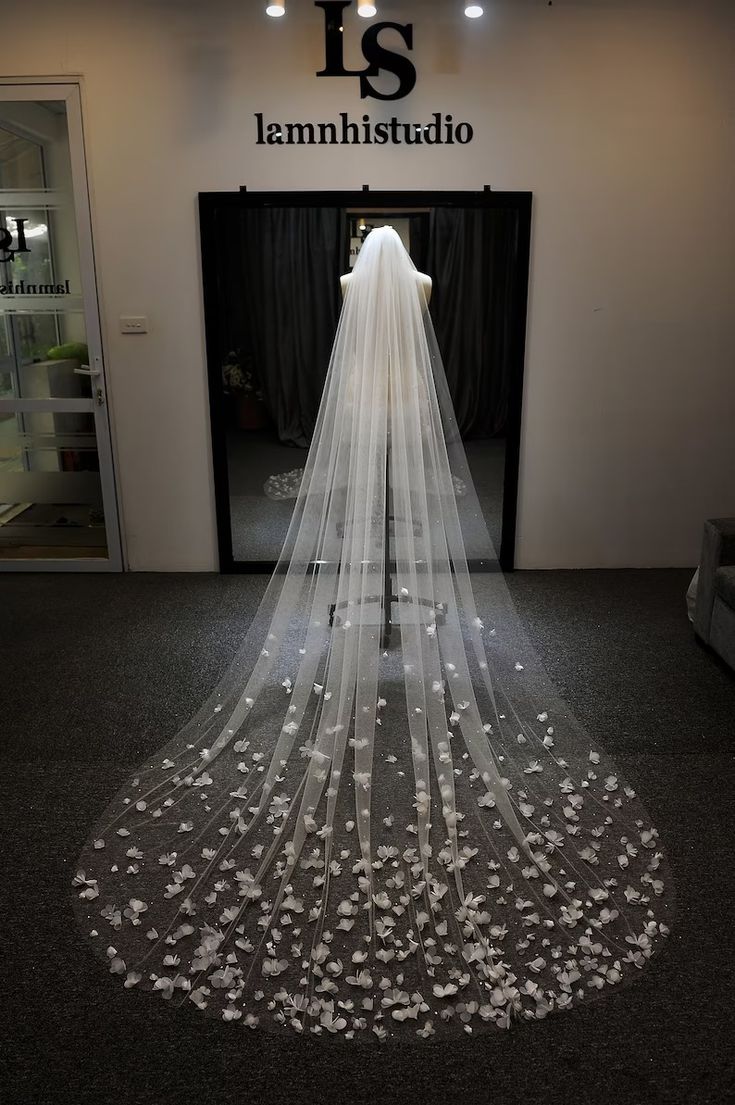 a white wedding veil is on display in front of a store sign that says it's iamhistidio