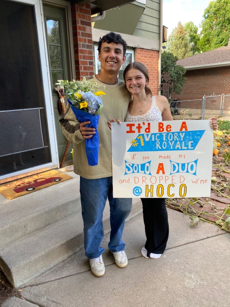 a man and woman are standing on the sidewalk holding a sign that says it's be a very royale