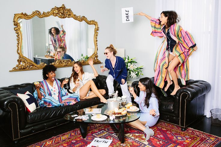 a group of women sitting around a living room table with food and drinks on it