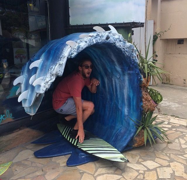 a man sitting on top of a surfboard in front of a large blue wave